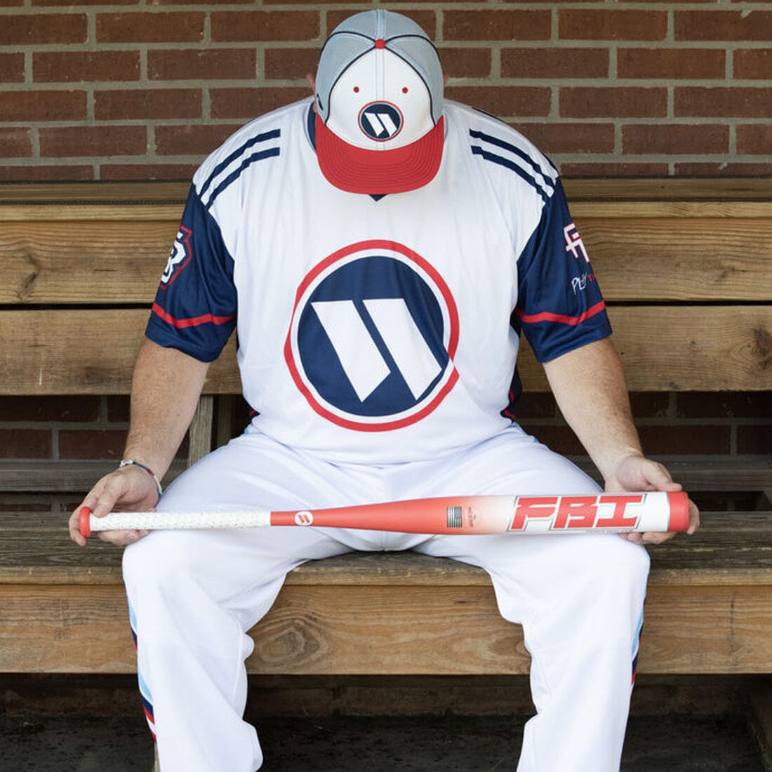 Chris Walker sitting on a dugout bench with his new Senior Softball Bat from Headbanger Sports