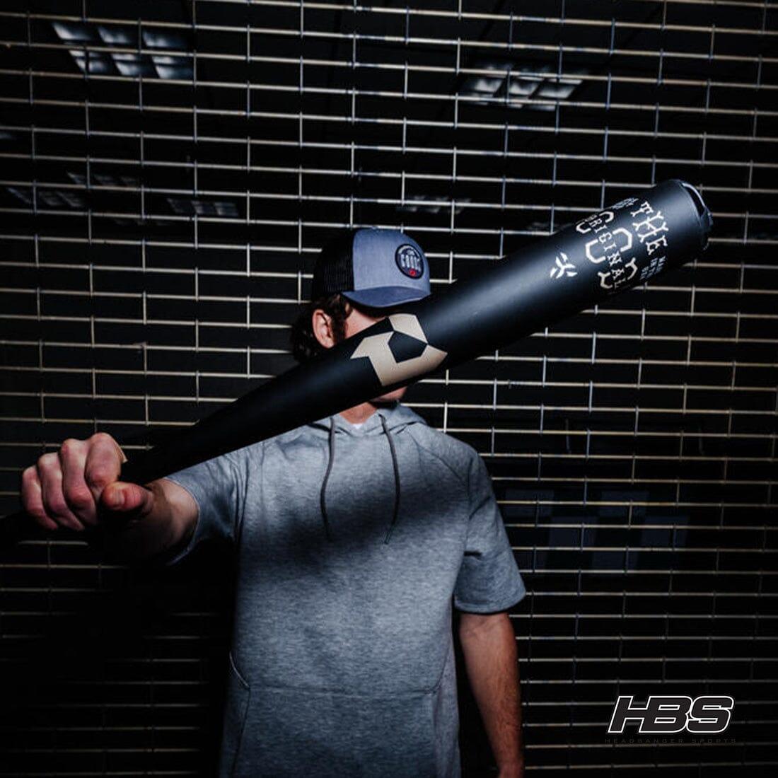 Baseball player holding the new 2025 Goods one Piece Baseball Bat with a Fence Behind Him